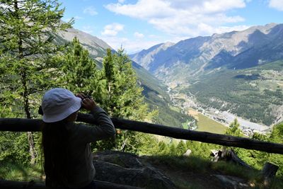 Girl wearing hat looking at mountains through binoculars