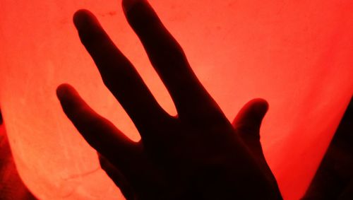 Close-up of silhouette hand against red fire