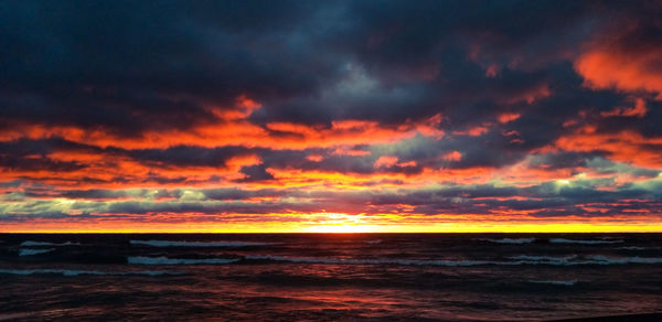 Scenic view of sea against dramatic sky during sunset