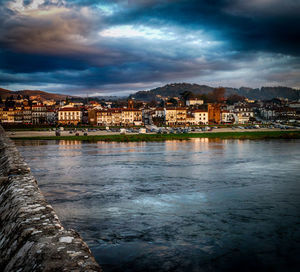 Buildings in town against cloudy sky