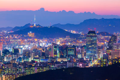 Illuminated buildings in city against sky during sunset