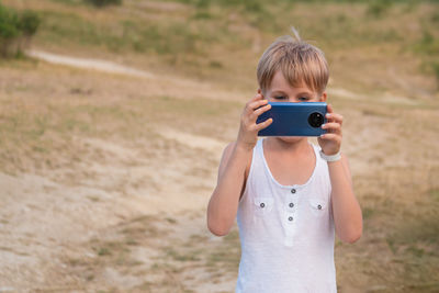 Full length of girl holding camera while standing on field