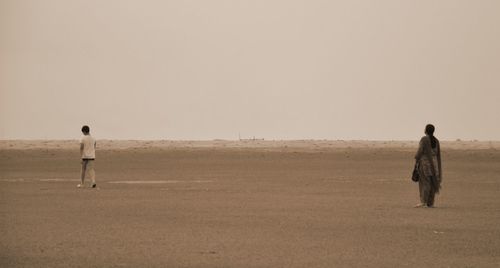 Rear view of man standing on field against clear sky