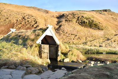 Built structure on rocks by land against mountain