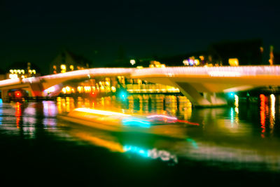 Illuminated bridge over river against sky at night