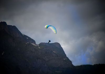 Low angle view of person paragliding against sky