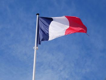 Low angle view of french flag waving against blue sky