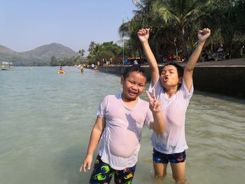 Portrait of happy brothers gesturing while standing in lake