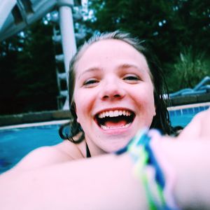 Close-up portrait of cheerful young woman in swimming pool