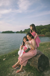 Side view of young woman sitting at lakeshore