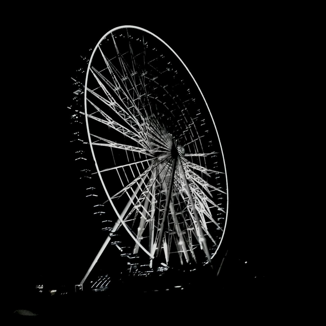 ferris wheel, night, arts culture and entertainment, amusement park ride, amusement park, low angle view, illuminated, sky, circle, clear sky, copy space, outdoors, motion, silhouette, no people, long exposure, spinning, large, built structure, wheel