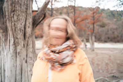 Midsection of woman against tree trunk