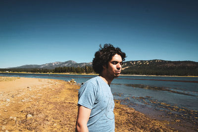 Young man looking away against clear blue sky