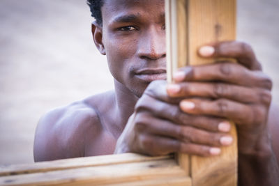 Close-up portrait of young man holding window frame