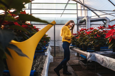 Woman standing by potted plants in greenhouse