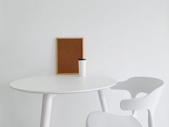 Close-up of empty chair on table against white wall