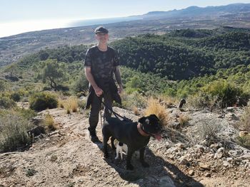 Portrait of man with dog standing on mountain