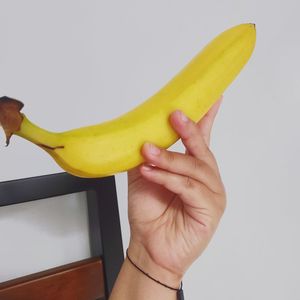 Close-up of hand holding fruit against white background