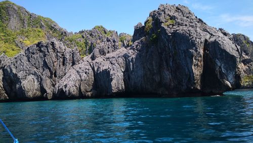 Scenic view of rocks in sea against blue sky