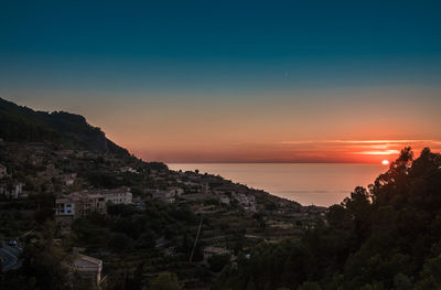 Scenic view of sea by buildings against sky during sunset