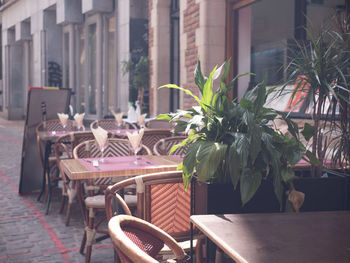 Empty chairs and tables at sidewalk cafe by building