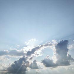 Low angle view of sunlight streaming through clouds