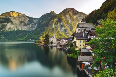 Houses by lake and mountains against sky