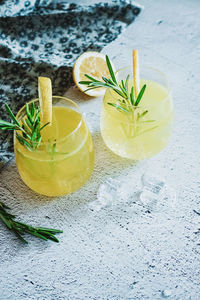 Cold cocktail, lemonade with lemon sliced, rosemary plant on white concrete background. drink photo