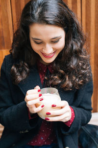 Beautiful young woman drinking water from while sitting outdoors