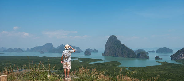 Rear view of man standing on mountain against sky