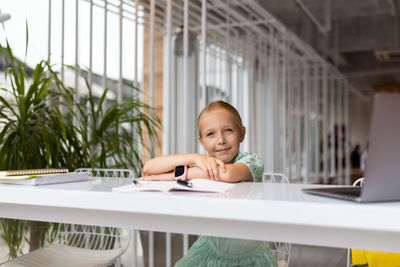 Portrait of smiling girl sitting on table