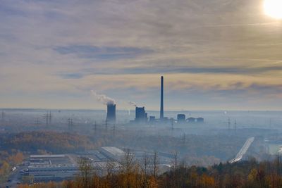 Smoke emitting from factory against sky