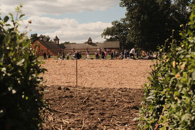Group of people on field by building against sky