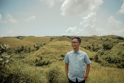 Portrait of man standing on field against sky