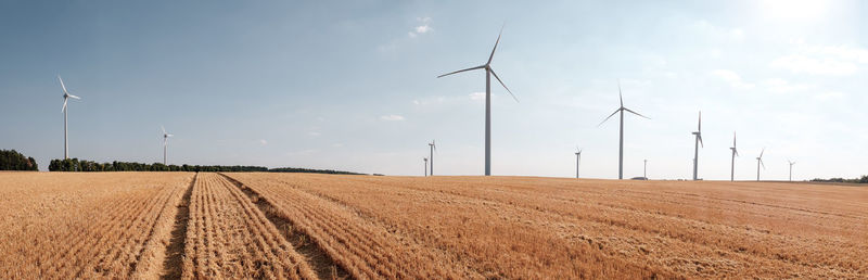 Wind turbines on field against sky