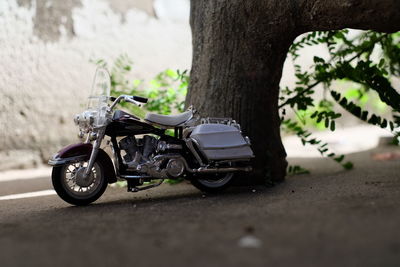 Toy motorcycle on field by tree