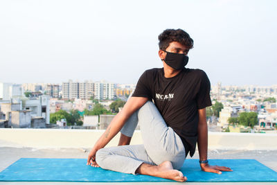 Young man in swimming pool against cityscape