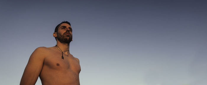 Low angle view of shirtless man standing against sky