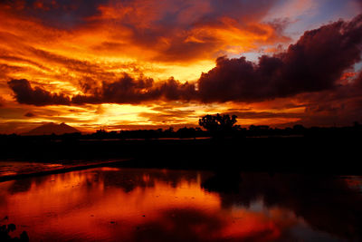 Scenic view of dramatic sky over silhouette landscape during sunset