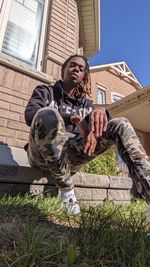 Low angle view of young man sitting against building