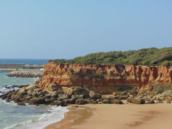 Cliff by sea against clear sky