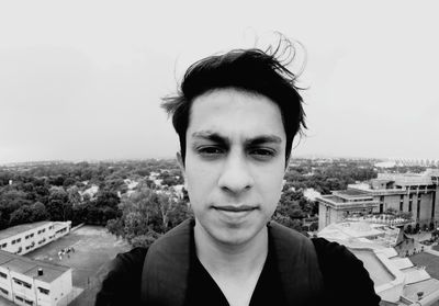 Portrait of young man with townscape against sky