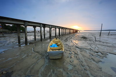 Boat moored at beach against sky during sunset