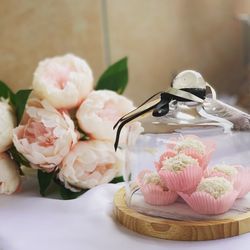 Close-up of sweet food glass container by flowers on table