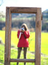 Woman with camera seen through window frame