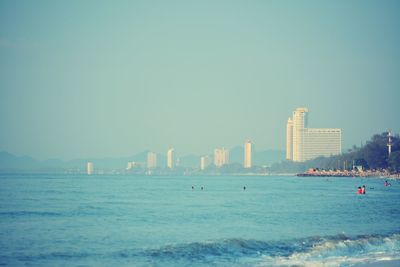 Sea by buildings against clear sky