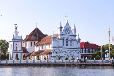 Buildings by river against sky in city