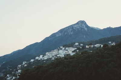 Townscape by mountains against clear sky