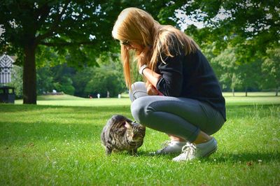 Woman stroking cat on grass