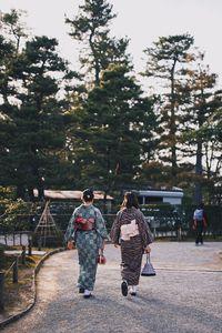 Rear view of couple walking by trees